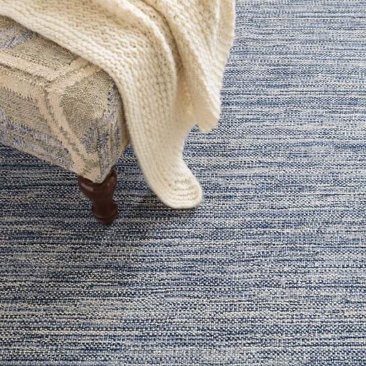 Bella Navy Woven Wool Rug styled with a accent chair and throw. Styled view.