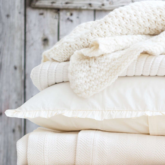 Ivory bedding textiles. Styled view.