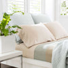 Light pink and light blue pillows on a made up bed. Styled view.