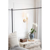 Fisher Single Sconce styled beside a neutral bed with decor and greenery. Styled view.