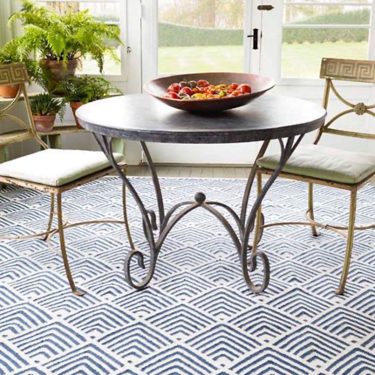 Cleo Navy Indoor/Outdoor Rug styled under metal patio furniture. Styled view.