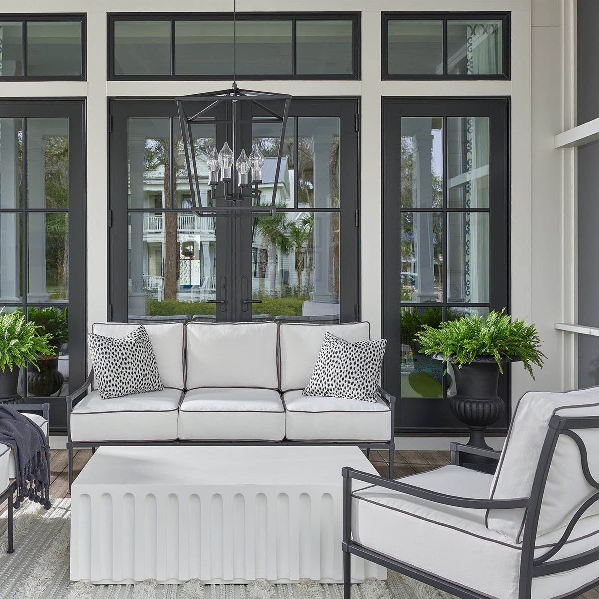 Coleford Outdoor Lantern styled above neutral outdoor seating. Styled view.