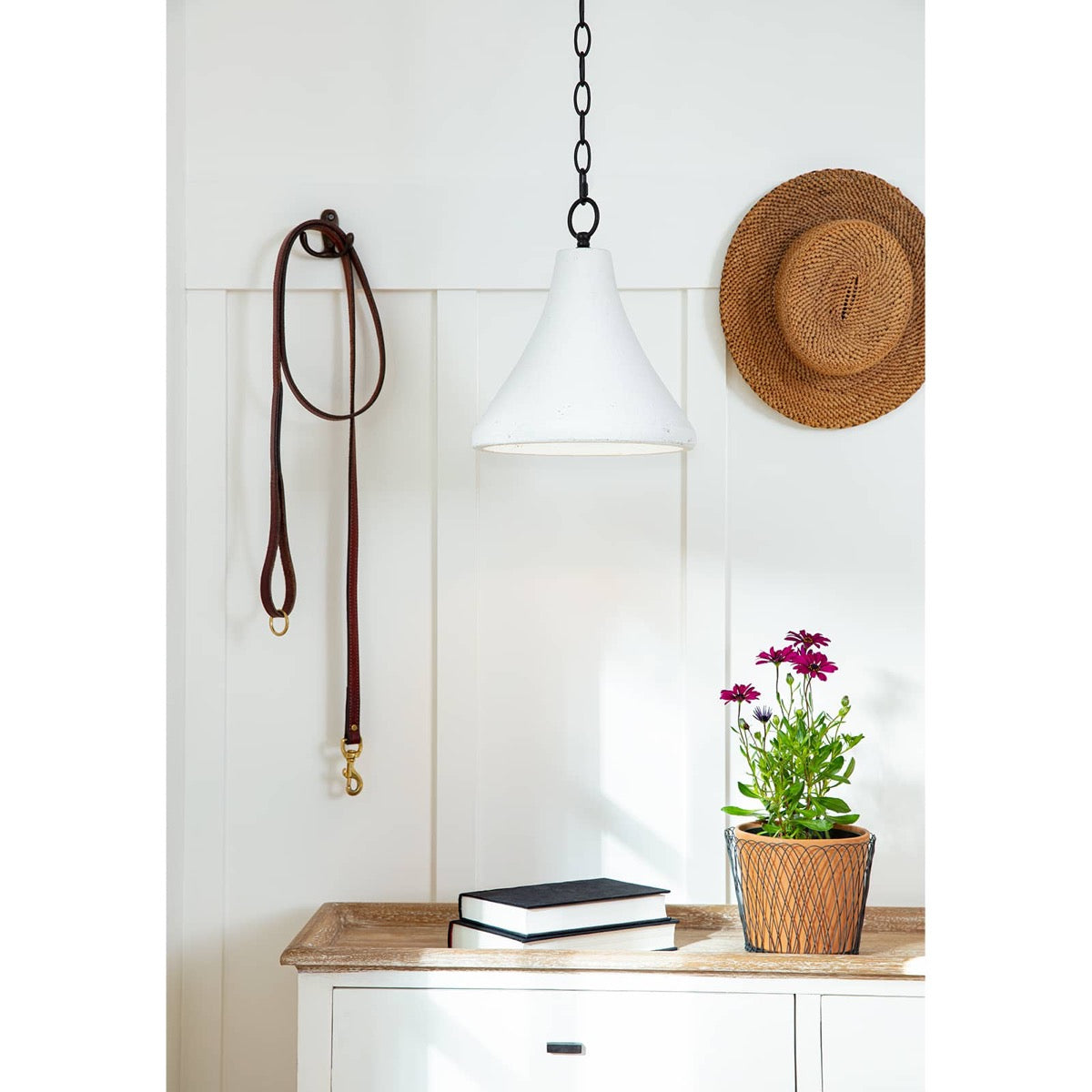 Billie Concrete Pendant - Small styled above a wood console table with books and greenery. Styled view.