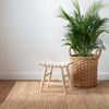 Dunes Natural Woven Jute Rug styled with a stool and woven basket. Styled view.