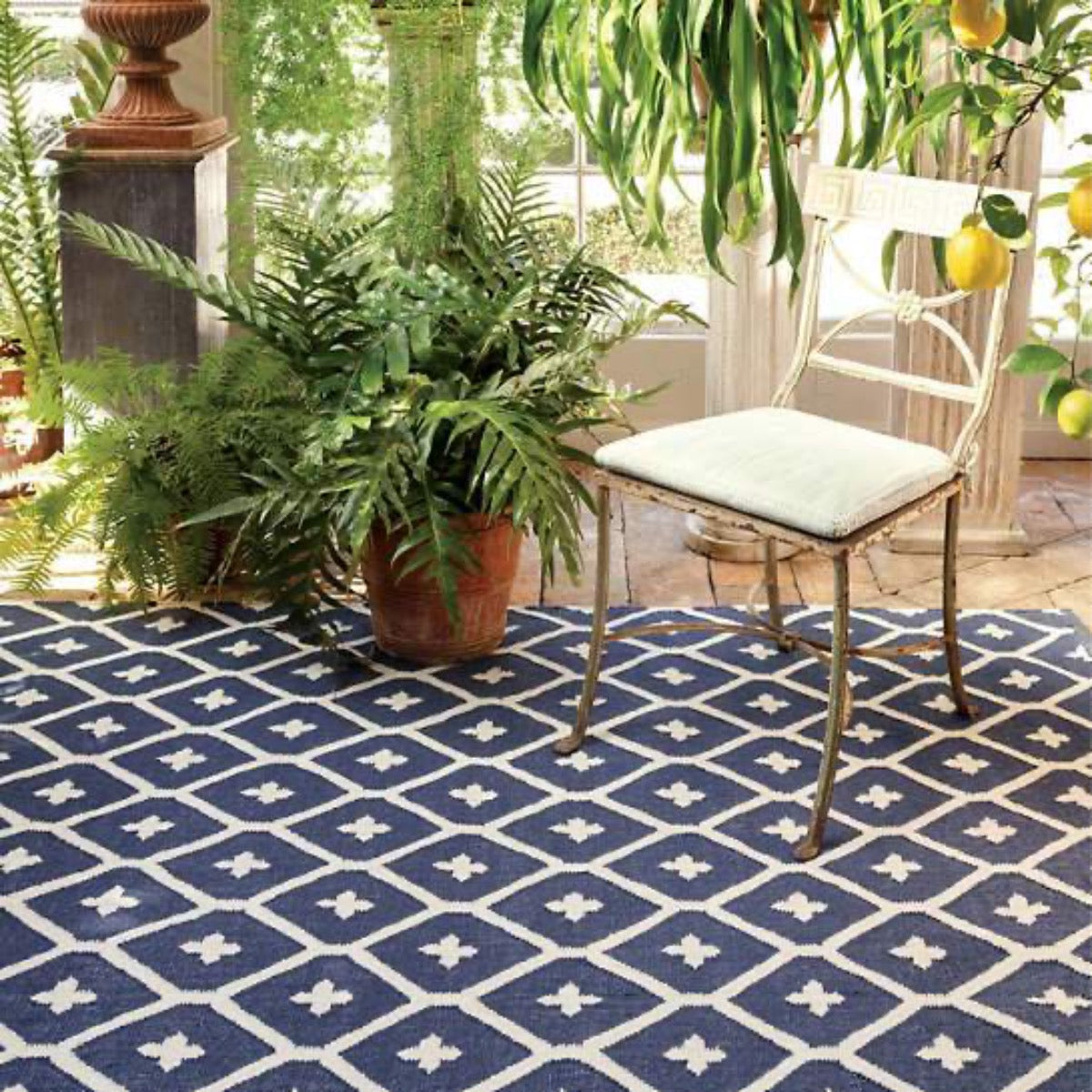Elizabeth Navy Indoor/Outdoor Rug styled under outdoor furniture and planters. Styled view.