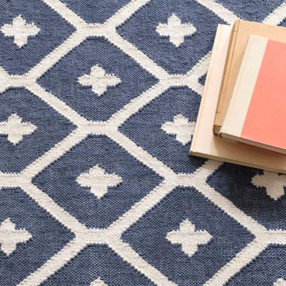 Elizabeth Navy Indoor/Outdoor Rug styled underneath books. Styled view.