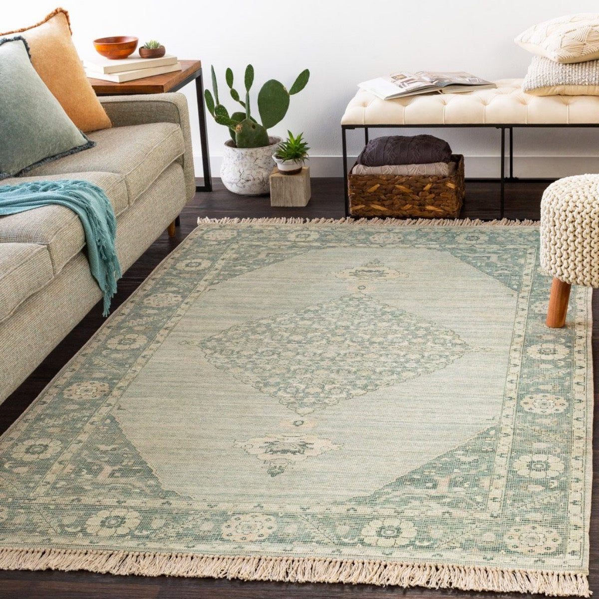 Ella Rug styled with a grey sofa, neutral stool and greenery. Styled view.