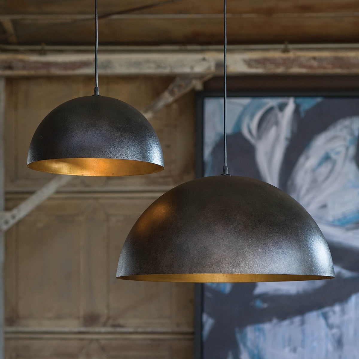 Flynn Pendant - Small Black & Gold styled in a rustic barn with artwork. Styled view.