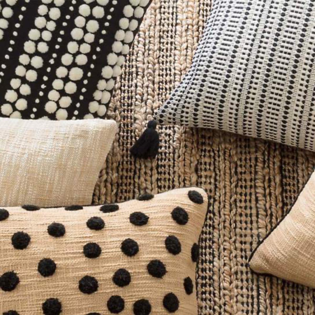 Gridwork Black Woven Jute Rug styled under black and white pillows. Styled view.
