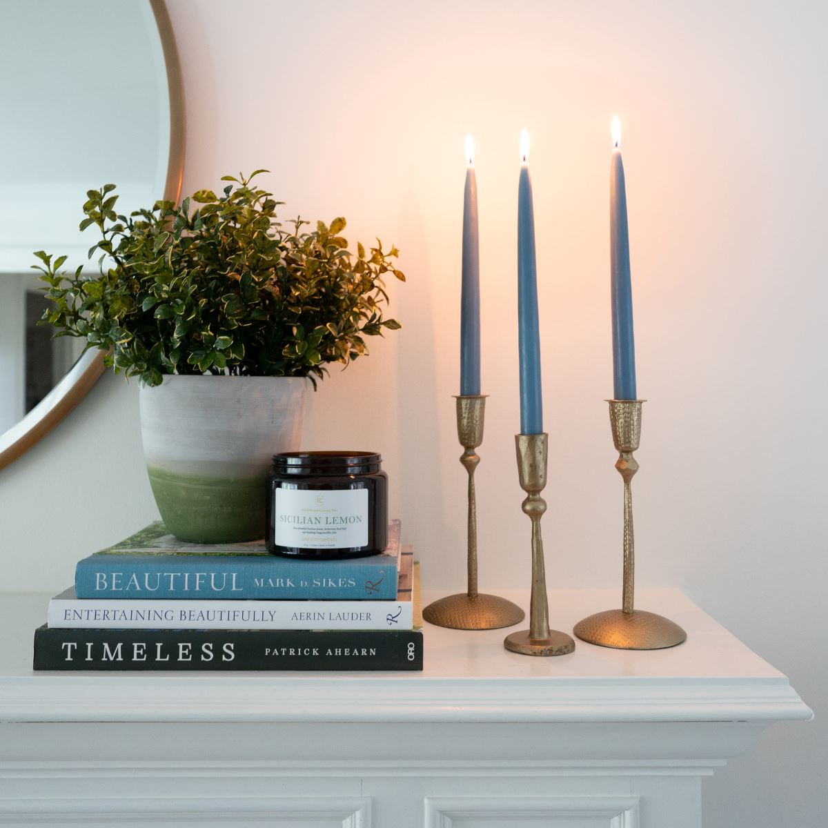 Hand-Dipped Danish Tapers - Blue/Grey styled with gold candle sticks and books. Candles lit. Styled view.