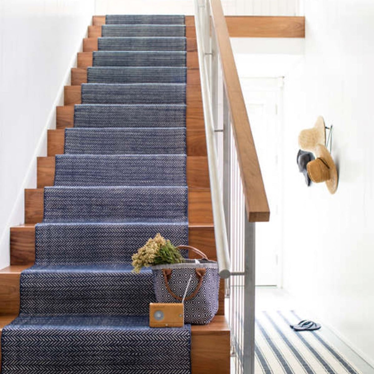 Herringbone Indigo Woven Cotton Rug as a runner on wood stairs. Styled view.