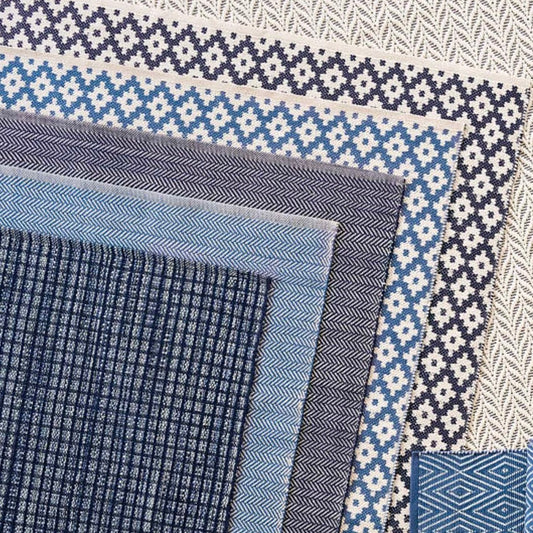 Herringbone Indigo/White Indoor/Outdoor Rug layered with blue rugs. Styled view.