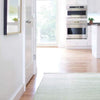 Herringbone Ocean Woven Cotton Rug styled in a white kitchen. Styled view.