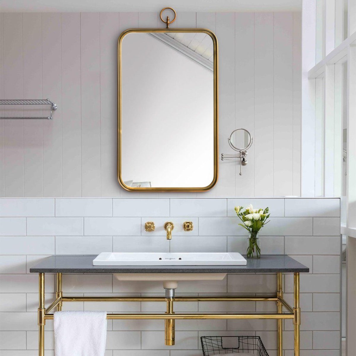 Hudson Mirror styled above a sink with golden fixtures. Styled view.