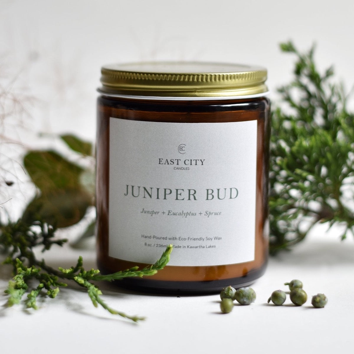 Juniper Bud Candle styled with greenery. Styled view.