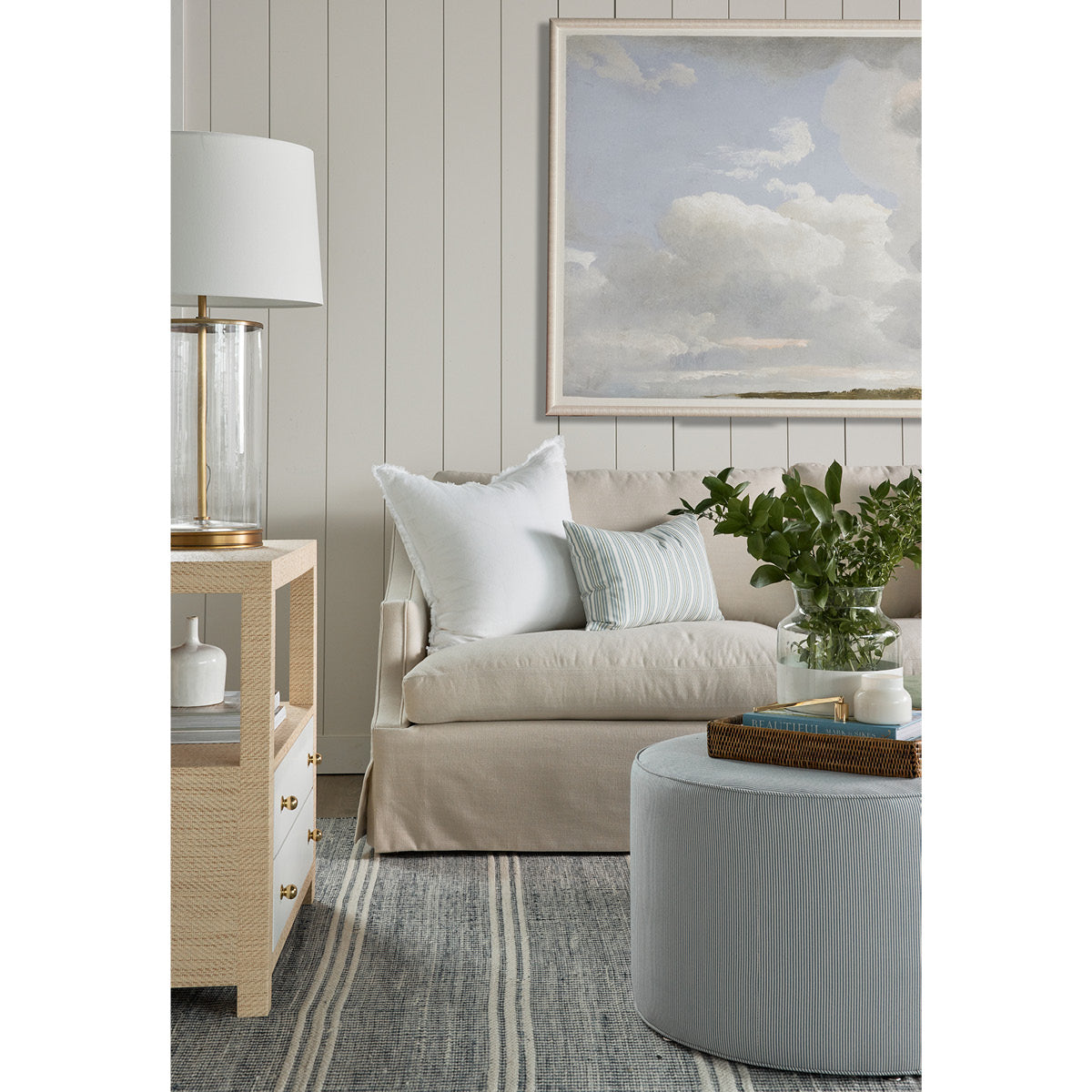 Kate Ottoman styled with rattan tray, blue rug and neutral sofa. Styled view.