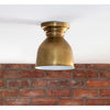 Pantry Flush Mount Natural Brass stayed against a brick wall. Styled view.