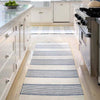 La Mirada Navy Woven Cotton Rug styled in a white kitchen. Styled view.