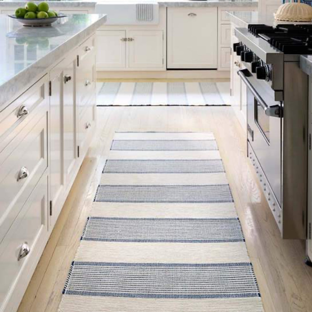 La Mirada Navy Woven Cotton Rug styled in a white kitchen. Styled view.