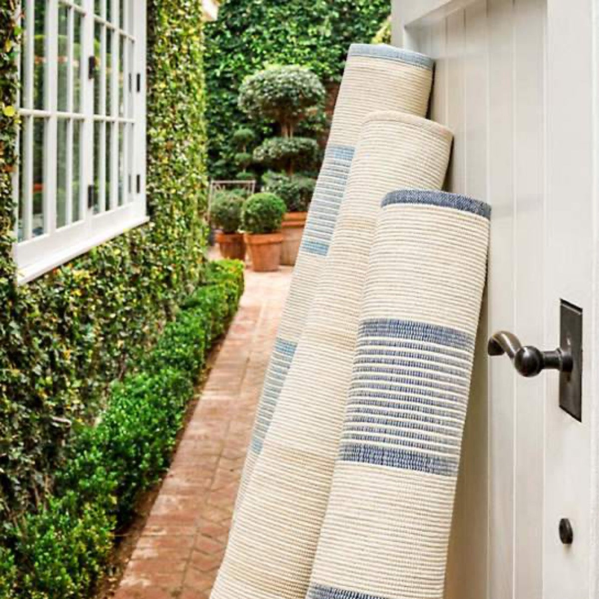 La Mirada Navy Woven Cotton Rug styled outdoors with striped rugs. Styled view.