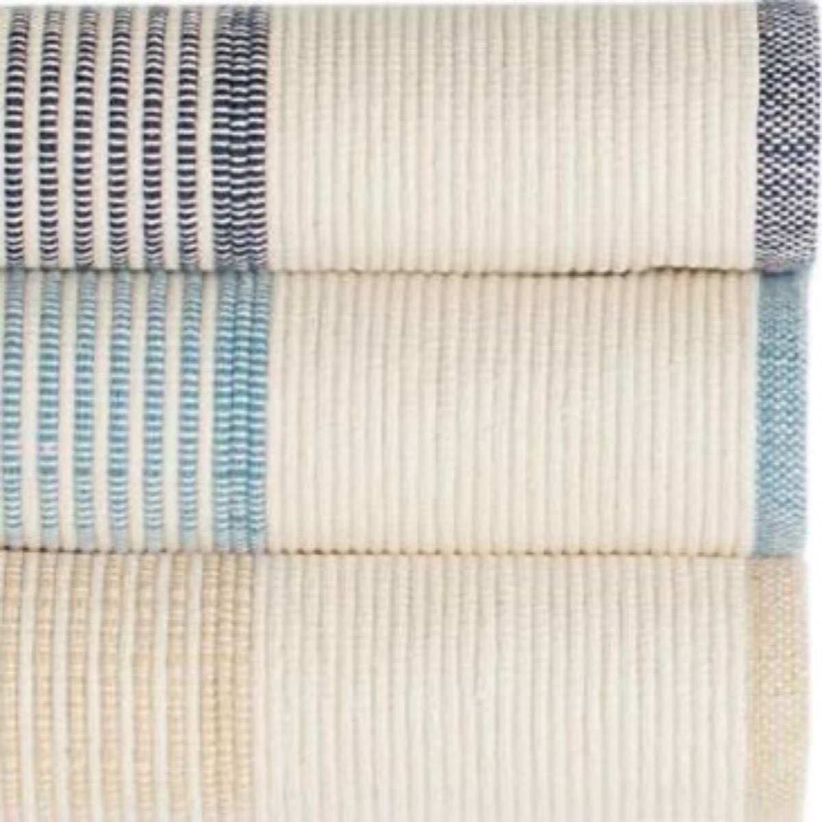 La Mirada Navy Woven Cotton Rug styled with striped rugs. Styled view.