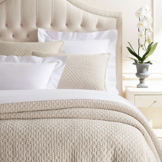 Lodi Alabaster Matelasse Coverlet styled on a neutral bed. Styled view.
