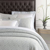 Lodi Blue Matelasse Coverlet styled with grey and white bedding. Styled view.