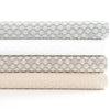 Folded stack of coverlets in multiple colours. Styled view.