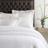 Lodi White Matelasse Coverlet styled with white sheets. Styled view.