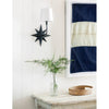 Celeste Sconce mounted above a distressed table with greenery. Styled view.