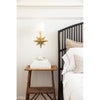 Celeste Sconce mounted above a side table beside a black table. Styled view.