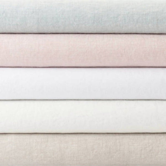Folded stack of lush linen duvet covers. Styled view.