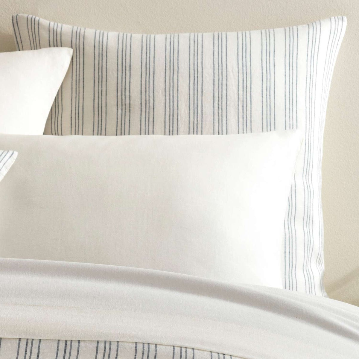 Lush Linen Stripe Slate Blue Sham styled with white sheets. Styled view.