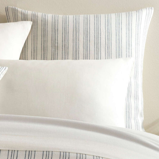 Lush Linen Stripe Slate Blue Sham styled with white sheets. Styled view.
