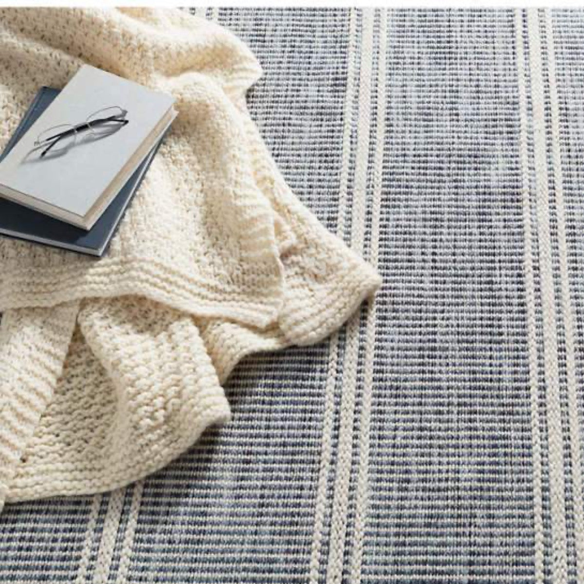 Malta Blue Woven Wool Rug styled under an ivory throw. Styled view.