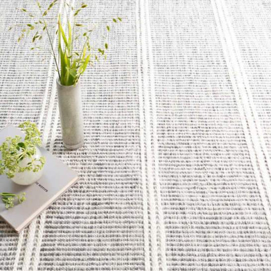 Malta Grey Woven Wool Rug styled under greenery. Styled view.