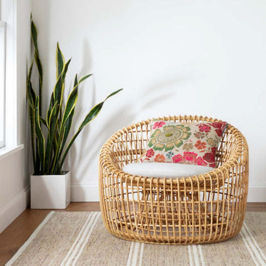 Malta Natural Woven Wool Rug styled under a wicker chair and planter. Styled view.