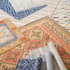 Malta Natural Woven Wool Rug styled in a pile of rugs. Styled view.