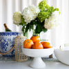Marble Pedestal Bowl styled with fruit on a white dining table. Styled view.