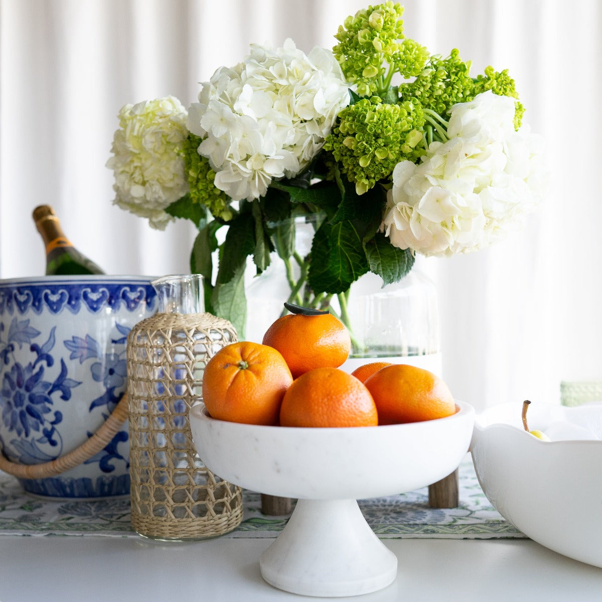 Marble Pedestal Bowl styled with fruit on a white dining table. Styled view.