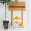 Marble Pedestal Bowl styled with orange and books. Wood cutting boards and olive trees. Styled view.