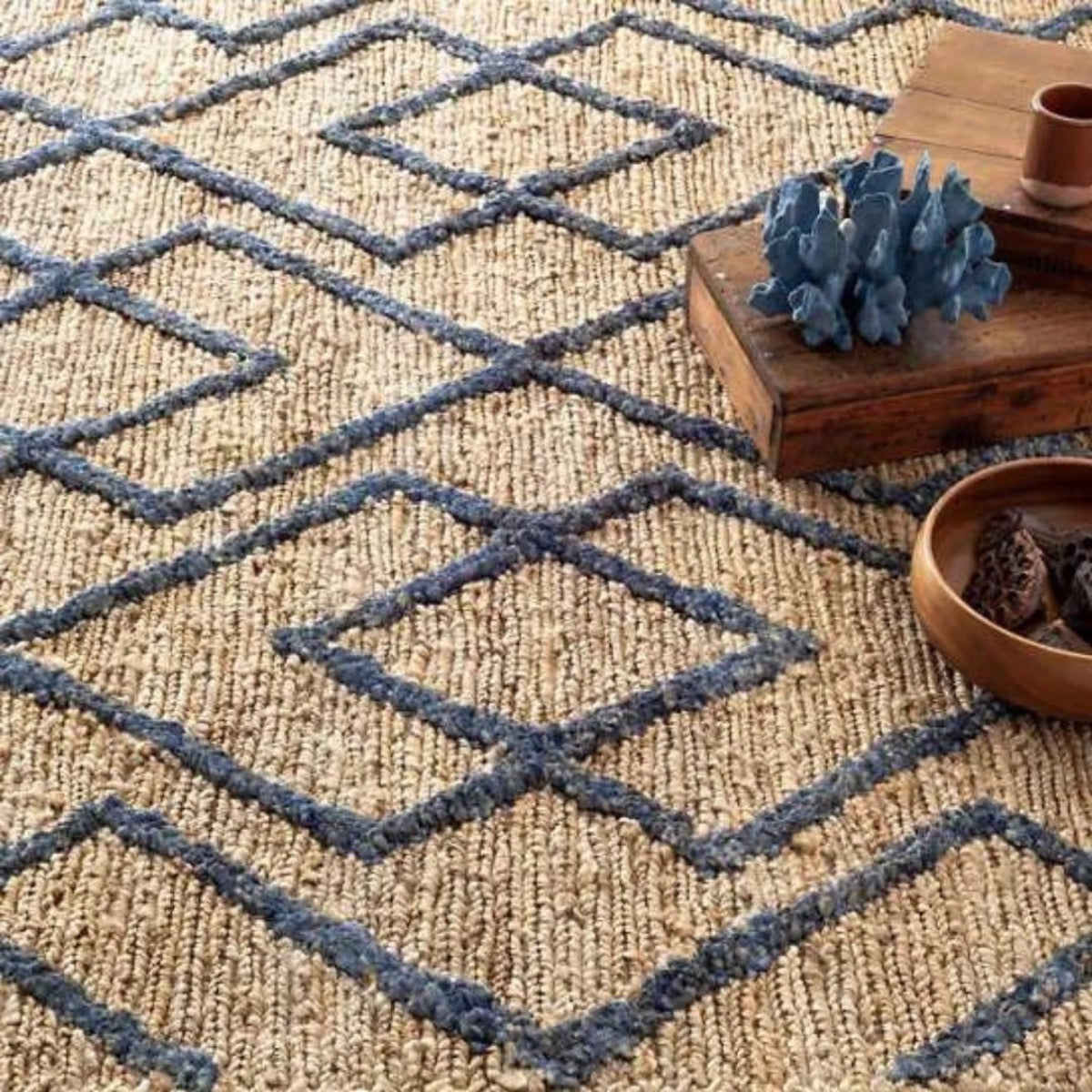 Marco Navy Jute Soumak Woven Rug styled under wood decor. Styled view.