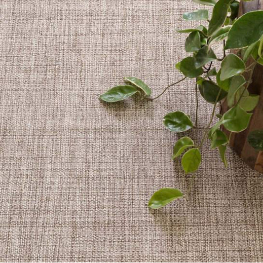 Marled Brown Woven Cotton Rug styled under greenery. Styled view.
