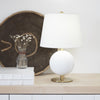 Megan Table Lamp styled on a wood surface with white books and neutral decor. Styled view.