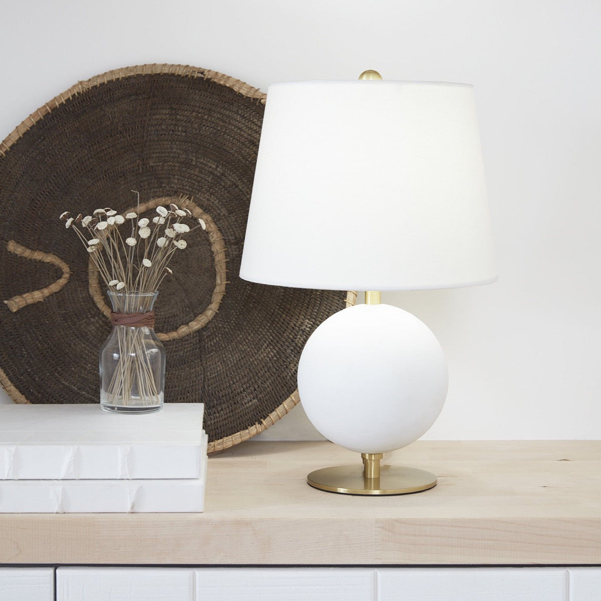 Megan Table Lamp styled on a wood surface with white books and neutral decor. Styled view.