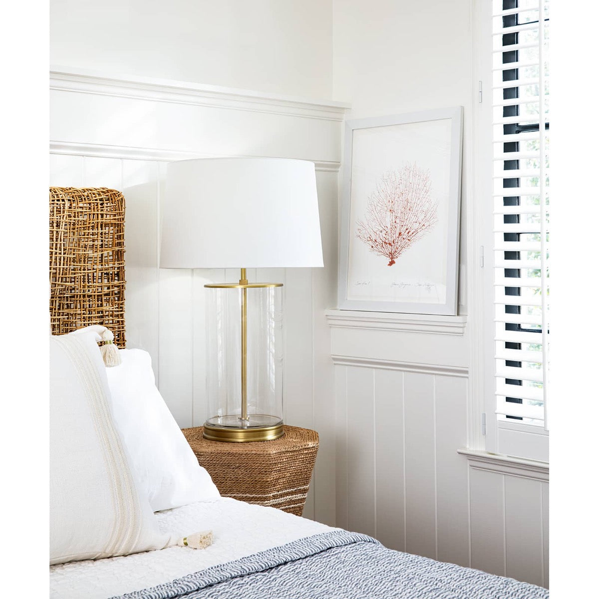 Magelian Glass Table Lamp styled on a bedside table with blue blankets. Styled view.