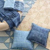 Ojai Wheat Loom Knotted Cotton Rug styled with blue throws. Styled view.