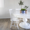 Pedestal Dining Table styled with white dining chairs and planters. Styled view.