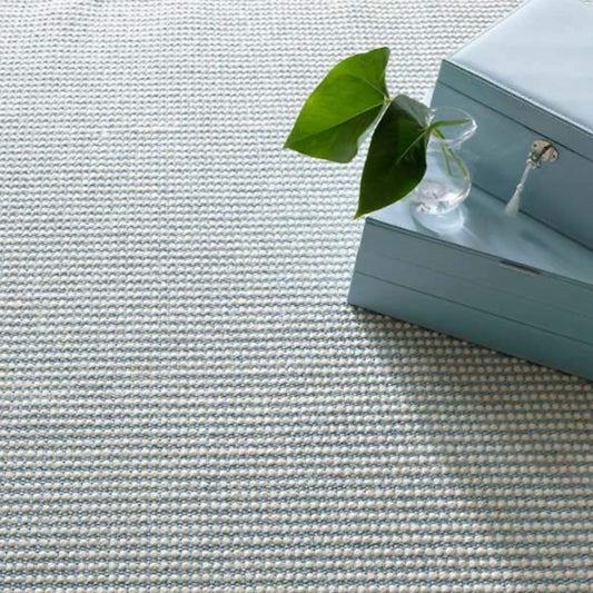 Pixel Sky Woven Sisal/Wool Rug styled under blue boxes. Styled view.