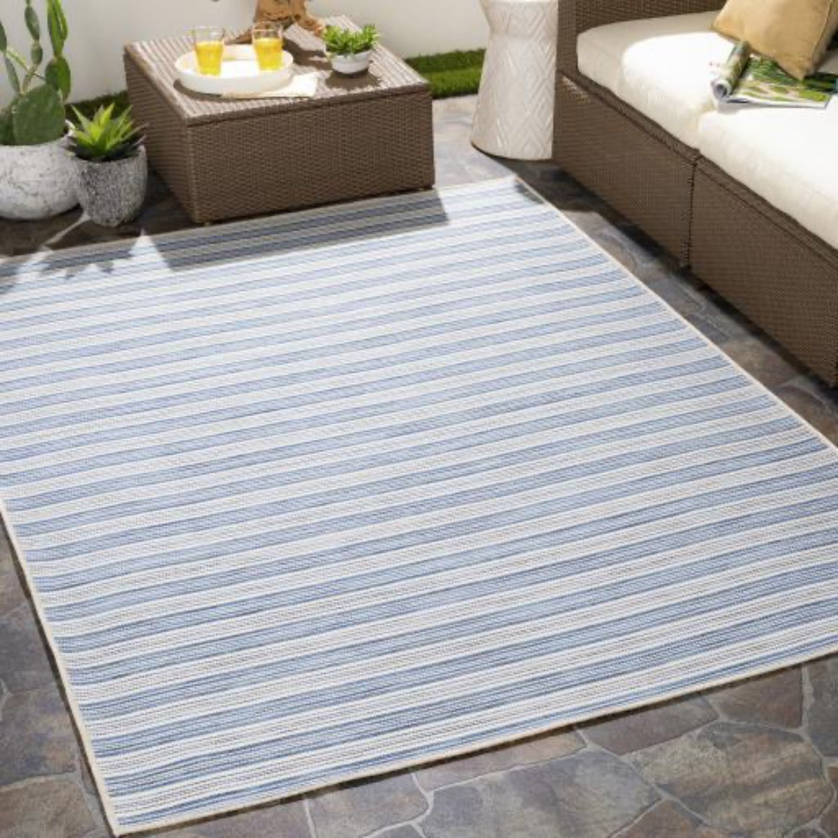 Portland Outdoor Rug - Blue styled with brown outdoor patio furniture. Styled view.